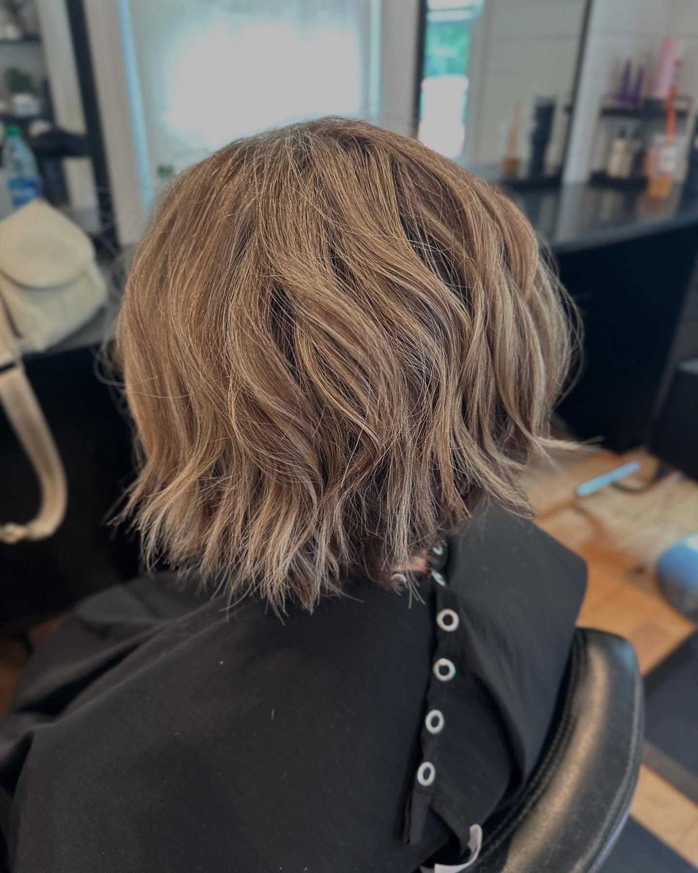 Short, wavy bob hairstyle being styled in a salon chair.